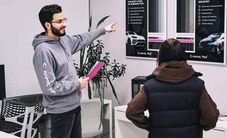 Salesperson presenting car options to a customer in a dealership showroom