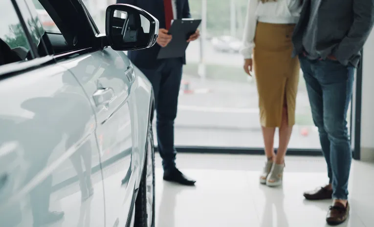 Car dealership consultation between salesperson and client discussing company car options