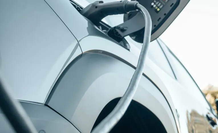 Electric hybrid car plugged into a charging station outdoors