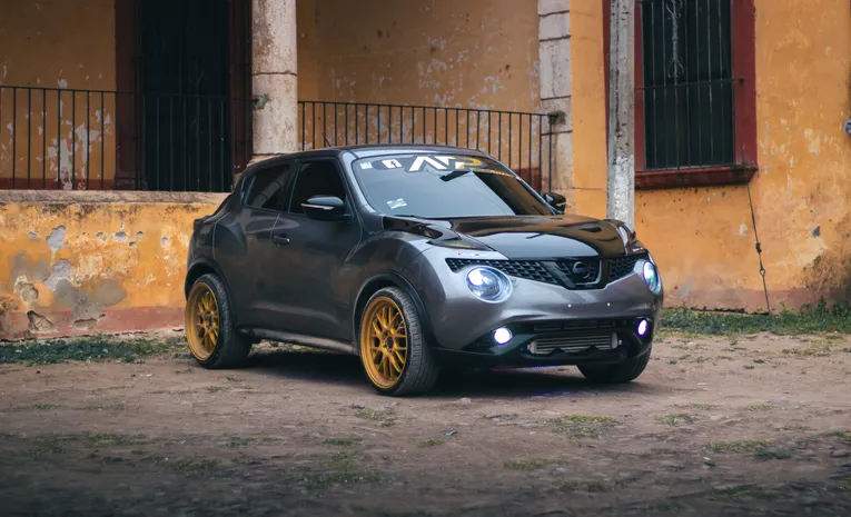Grey Nissan Juke parked with its lights on