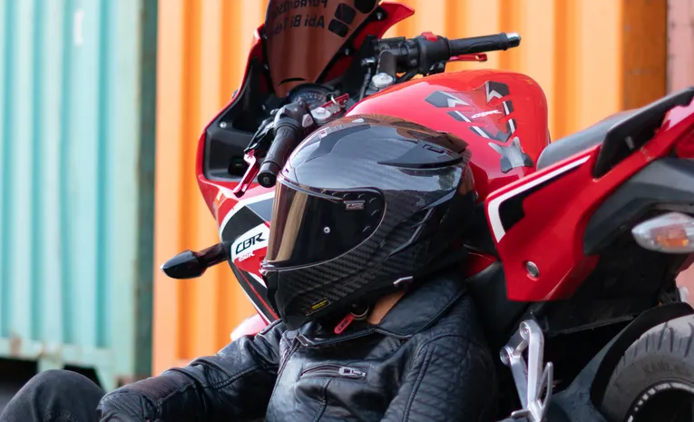 Rider wearing full face helmet and jacket standing with motorbike